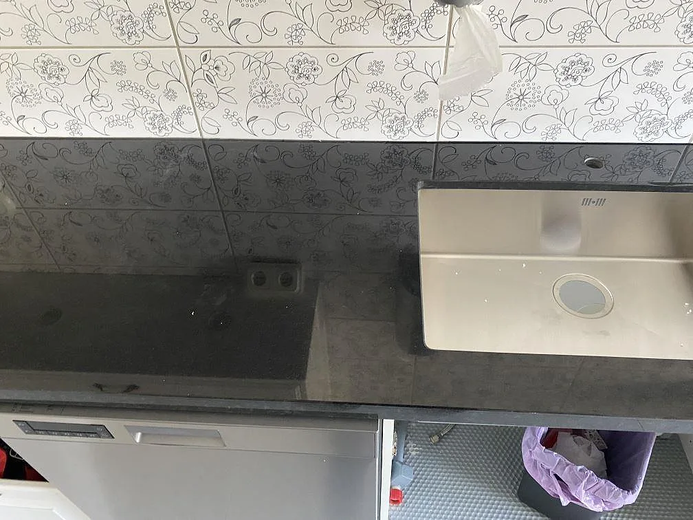 Polerad Nero Assoluto granitbänkskiva med rostfri diskho och mönstrat kakel i ett kök i Kristianstad.