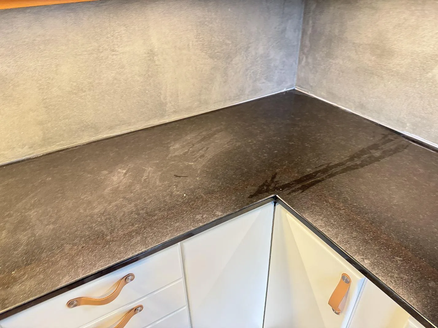 L-format hörn av köksbänkskiva i polerad svart Nero Assoluto granit med ljusa luckor i Kristianstad.