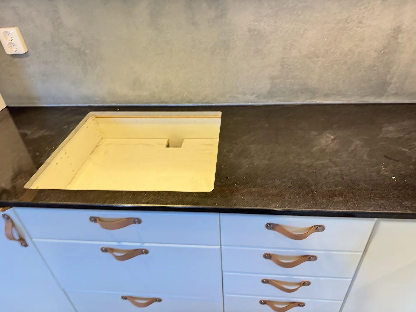 Polerad Nero Assoluto granitbänkskiva med rektangulärt urtag och ljusa köksluckor i Kristianstad.