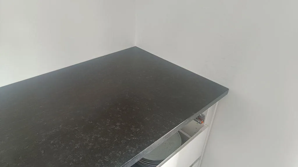 Hörndel av köksbänkskiva i svart Nero Assoluto granit med matt leather-finish i Askim.