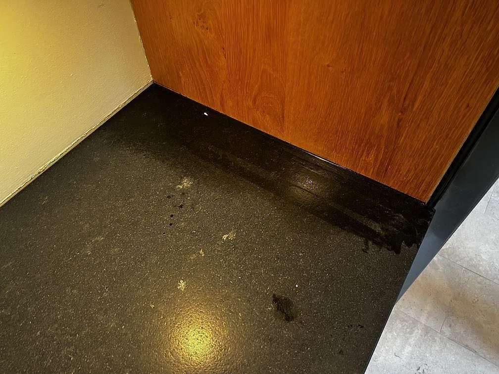 Detalj av matt Nero Assoluto Leather granit i hörn mot träpanel och vägg i ett kök i Höllviken.
