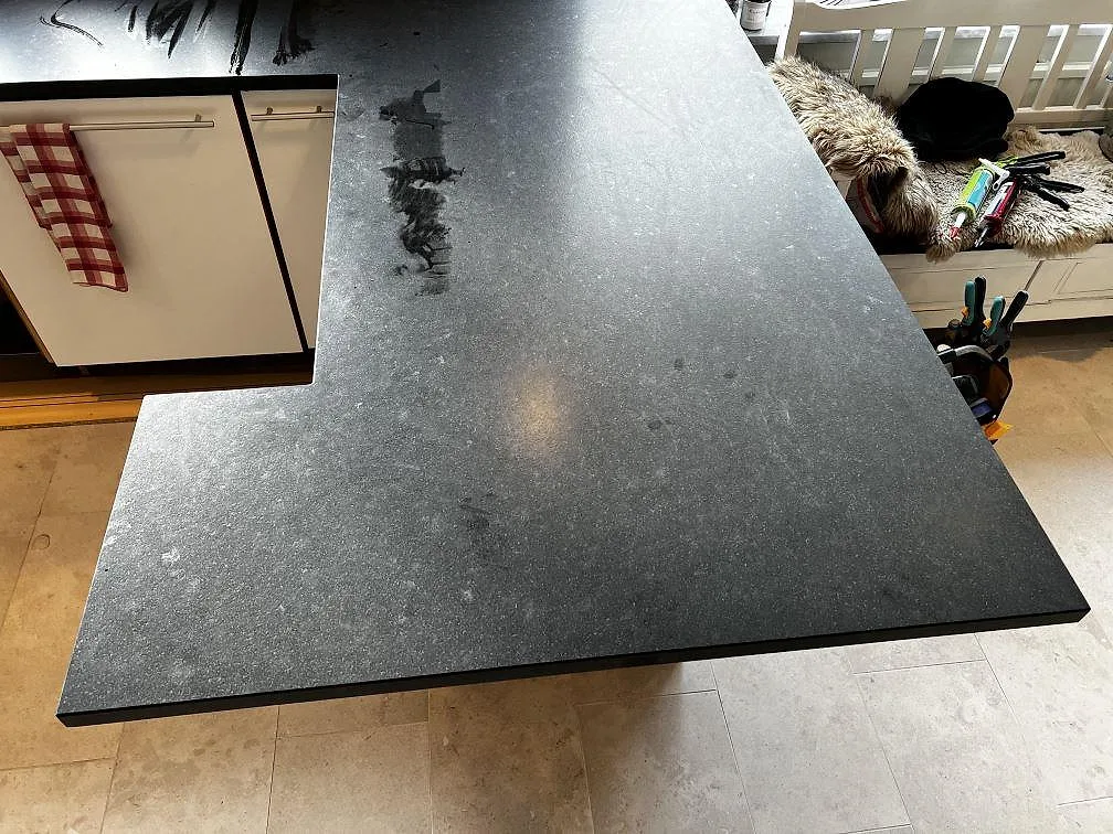 Stor peninsula i matt Nero Assoluto Leather granit med svart leatherfinish i ett kök under montering i Höllviken.