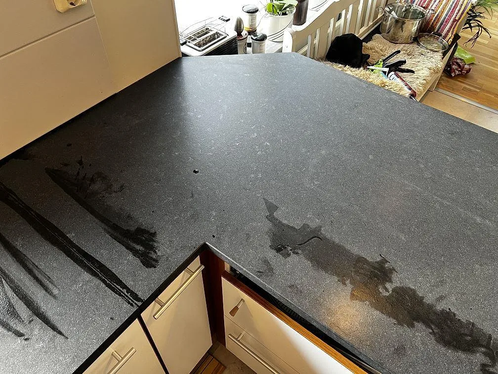 Närbild på L-formad köksbänkskiva i svart Nero Assoluto Leather granit med matt yta i Höllviken.