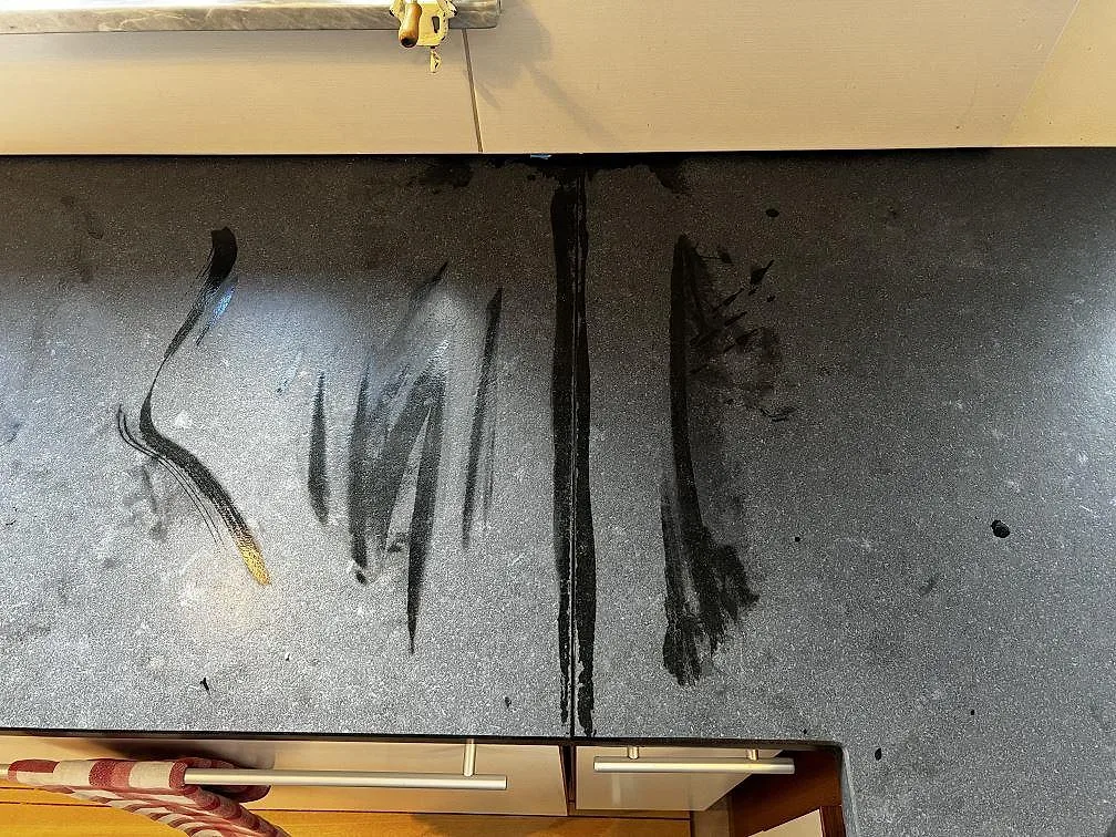 Matt köksbänkskiva i Nero Assoluto Leather med synlig skarv och monteringsspår vid vita luckor i Höllviken.