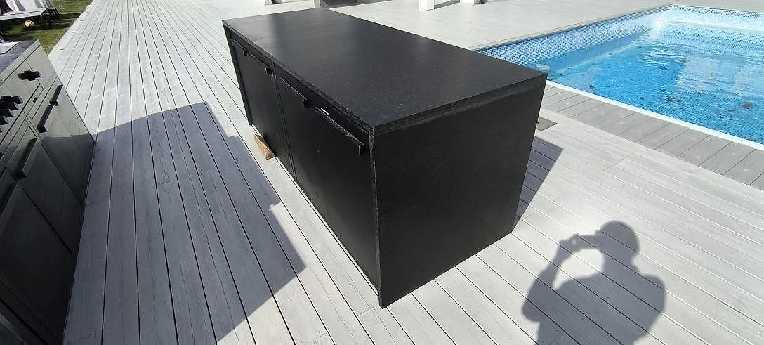 Närbild av matt Nero Assoluto Leather granitskiva som arbetsyta på svart utekök med trädäck i Södertälje.