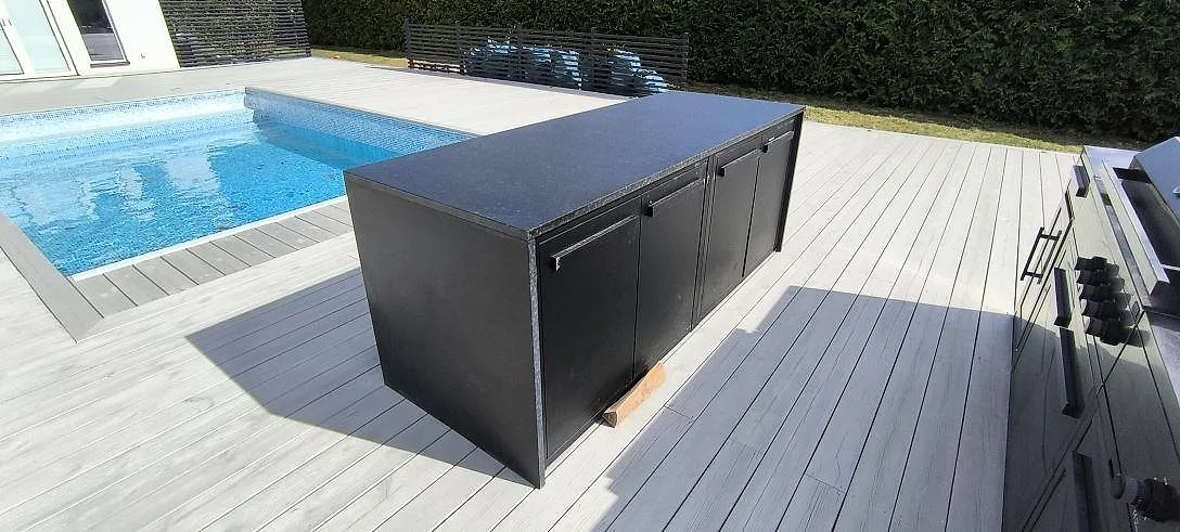Köksbänkskiva i matt Nero Assoluto Leather, svart granit, på en uteköksmodul vid pool i Södertälje.