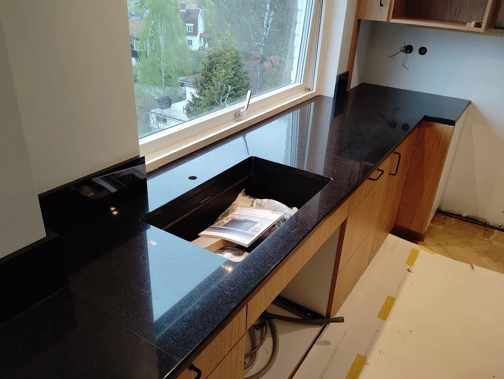 Polerad bänkskiva i svart granit Nero Assoluto vid fönster, med utskärning i stenen och träinredning i Lidingö.
