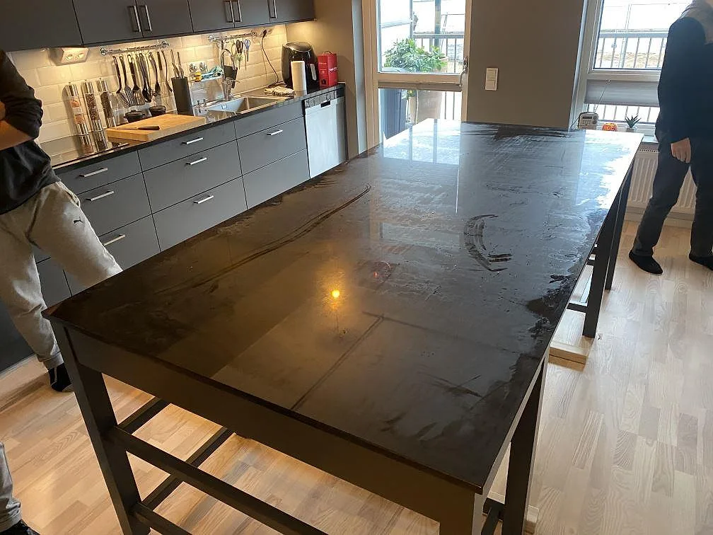 Köksö i polerad Nero Assoluto granit installerad i ett kök i Limhamn, med den mörka stenskivan i blickfånget mot grå köksluckor.