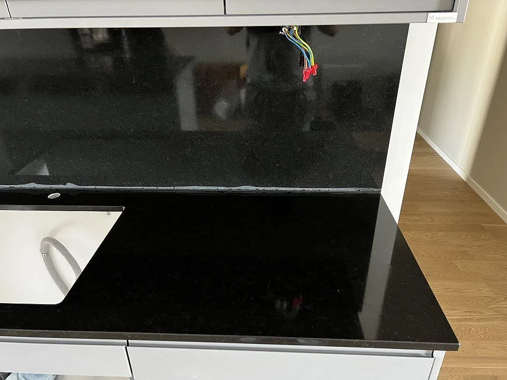 Närbild på matt Nero Assoluto granit som bänkskiva och stänkskydd med synlig eldragning i köket i Limhamn.
