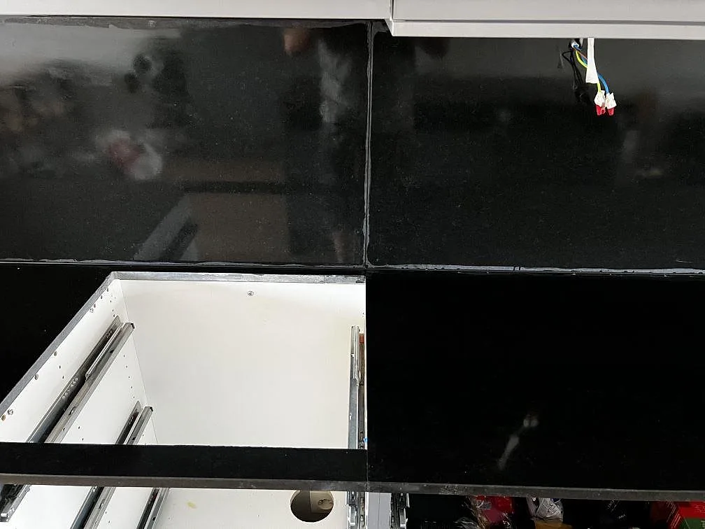 Detalj av skarv mellan bänkskiva och stänkskydd i matt Nero Assoluto granit i ett kök i Limhamn.