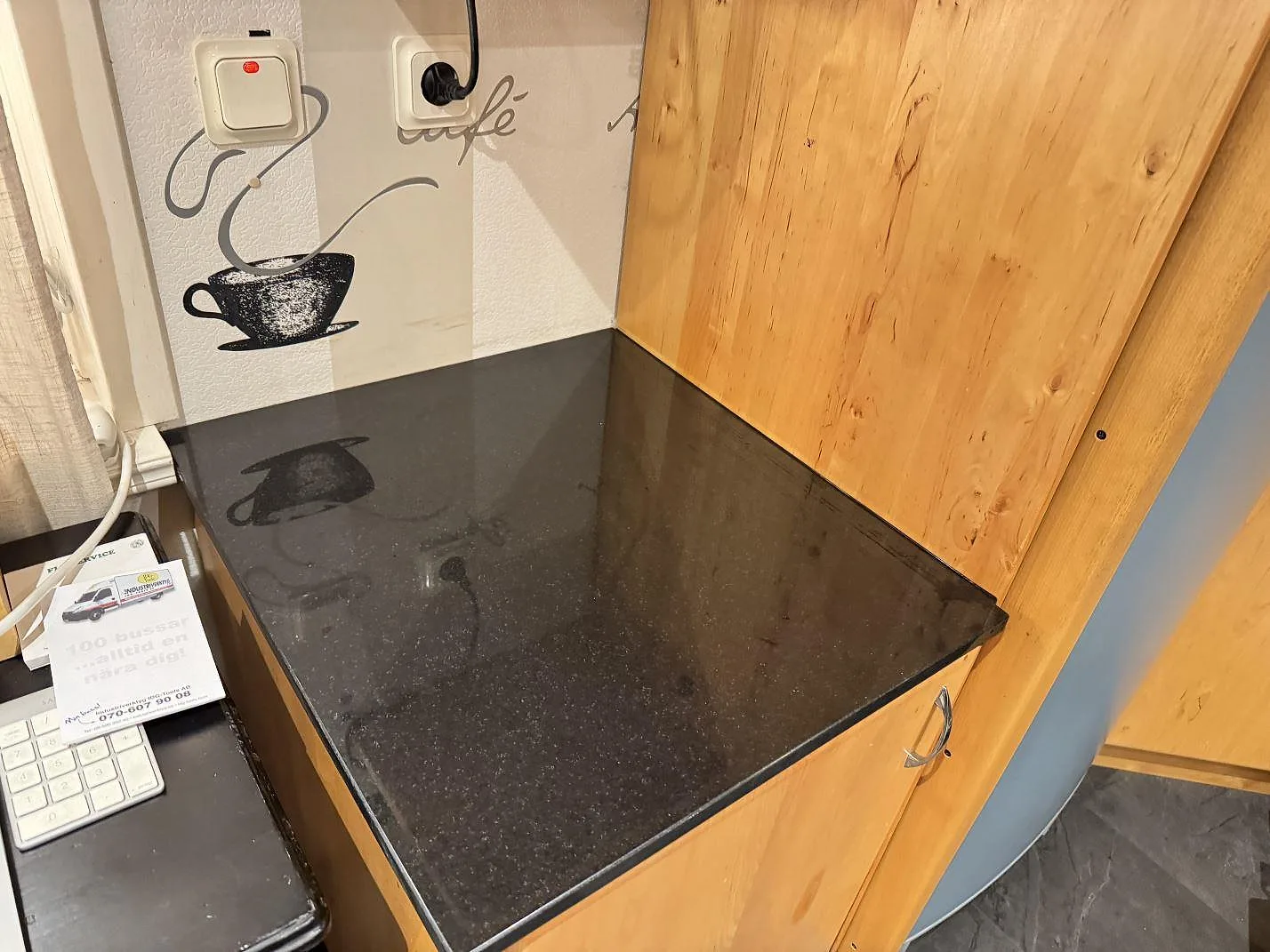 Separat avställningsyta i polerad Nero Assoluto granit vid träskåp i köket i Linneryd.