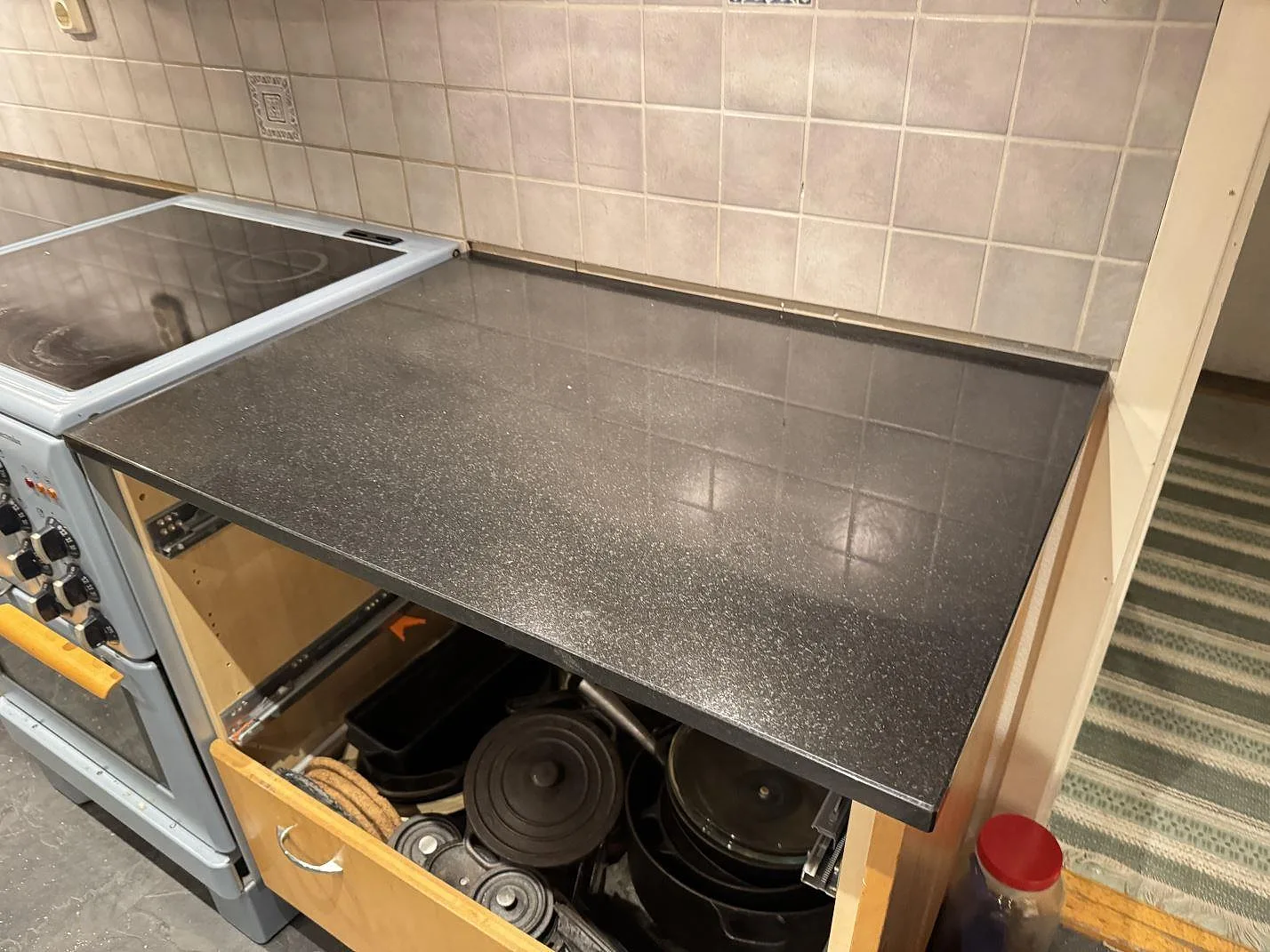 Polerad Nero Assoluto granit som arbetsyta intill spis i ett kök med träinredning i Linneryd.