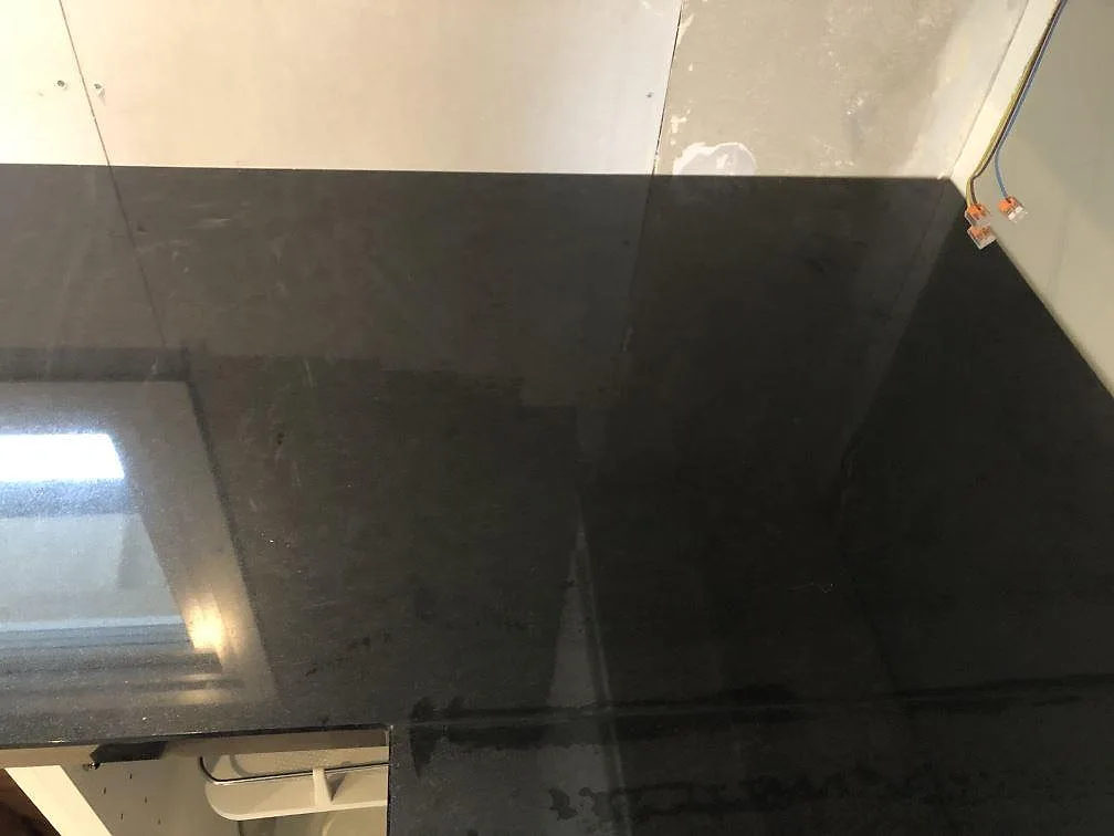Svart Nero Assoluto granitbänkskiva, polerad, mot gipsvägg under montering i ett kök i Lomma.