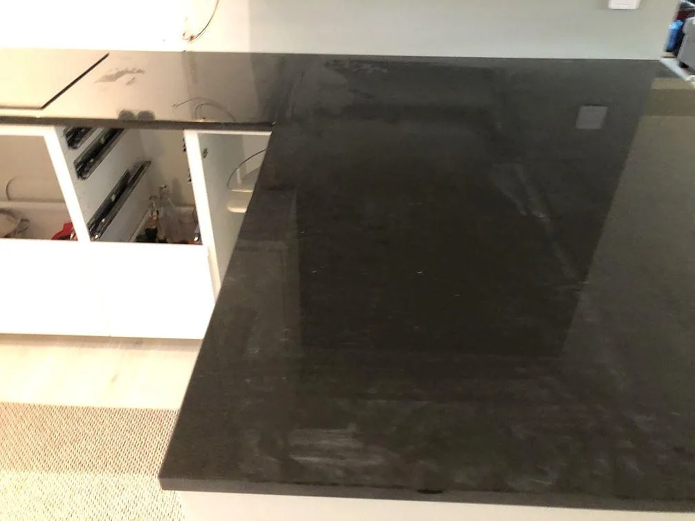 Polerad svart Nero Assoluto granitbänk över öppna lådor i ett kök under montering i Lomma.