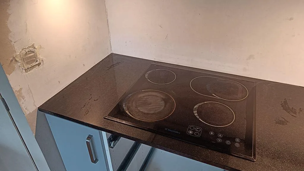 Hällzon i polerad Nero Assoluto granit med mörk glashäll och 20 mm kant i ett kök i Lomma.