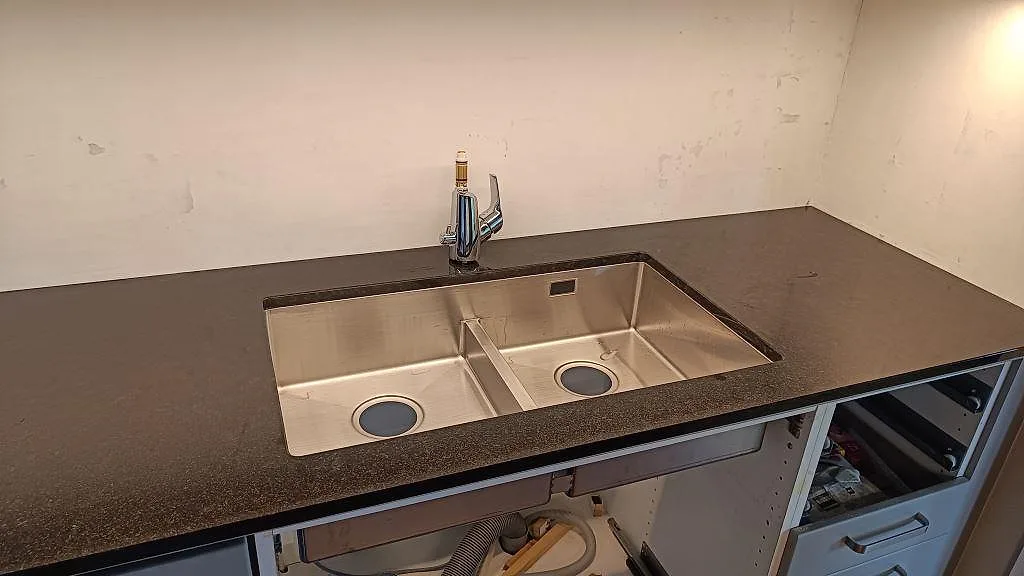 Rostfri dubbelho och blandare monterade i en polerad Nero Assoluto granitskiva i köket i Lomma.