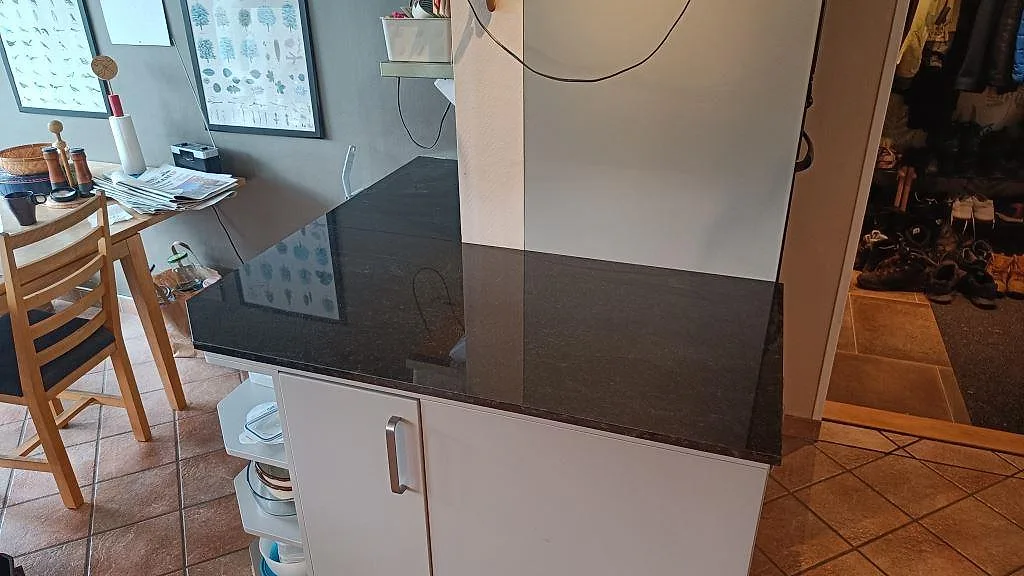Översiktsbild av polerad Nero Assoluto granit på en mindre köksbänk med vit inredning i Lomma.