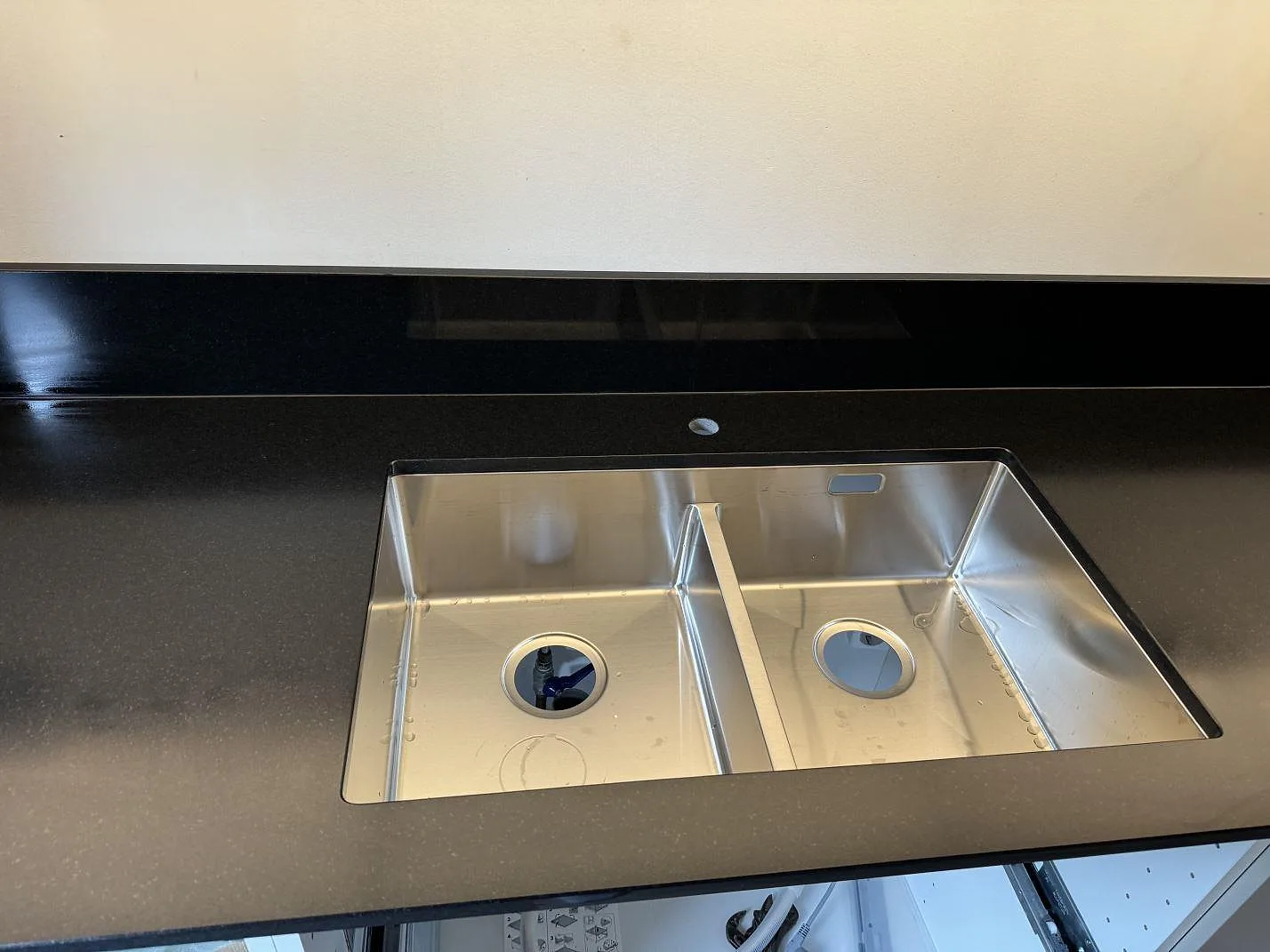 Detalj av matt Nero Assoluto granit runt den rostfria dubbelhon och stänkkanten i ett kök i Lomma.