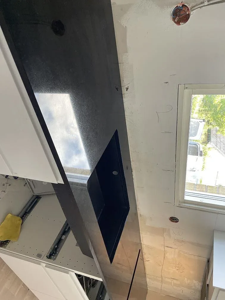 Väggbänk i polerad Nero Assoluto granit med hällzon och blank svart yta i ett kök under montering i Lund.