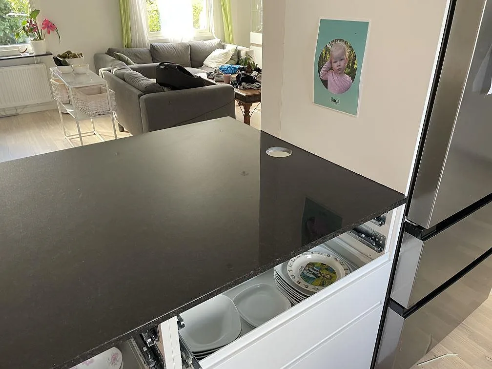 Svart köksbänkskiva i Nero Assoluto granit på halvö mot vardagsrum, polerad yta och öppna köksstommar i Lund.