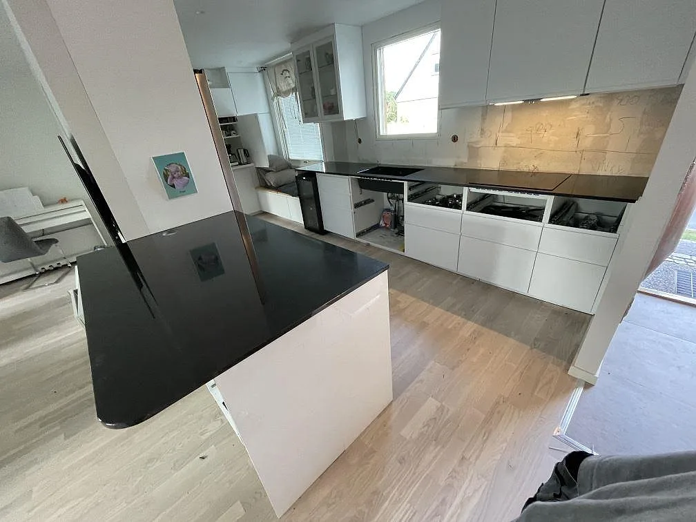 Köksbänkskiva i svart Nero Assoluto granit, polerad, med rundad halvö och väggbänkar i ett kök i Lund.