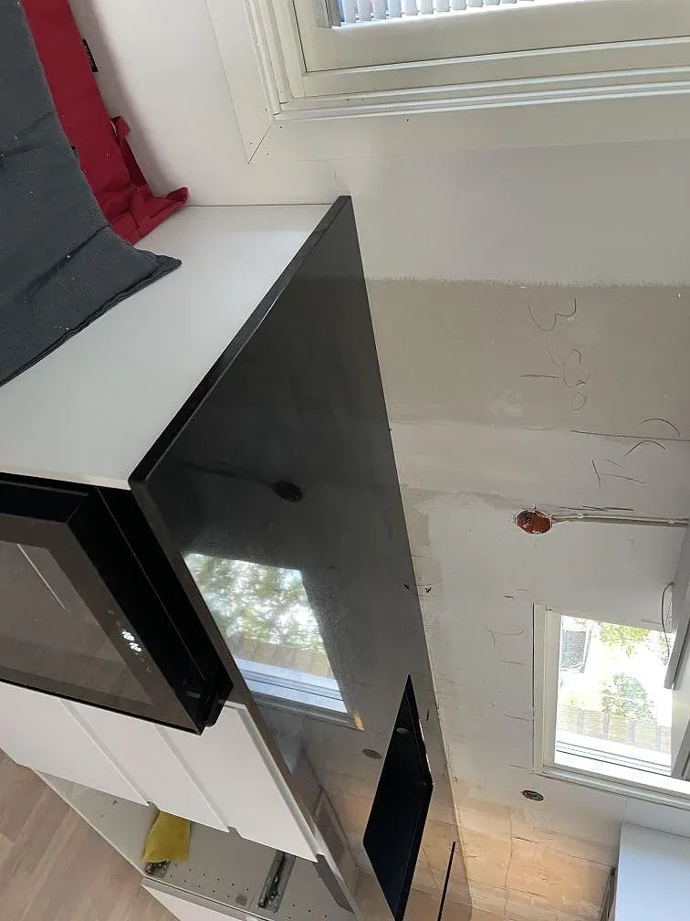 Polerad Nero Assoluto granit som mörk köksbänkskiva vid häll och väggsida under montering i Lund.