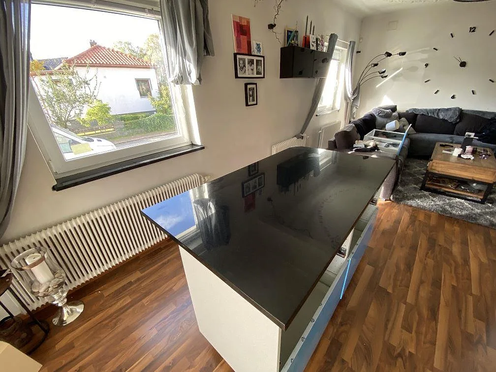 Köksbänkskiva i svart Nero Assoluto, polerad granit, på en köksö med ljus stomme i ett öppet kök i Malmö.