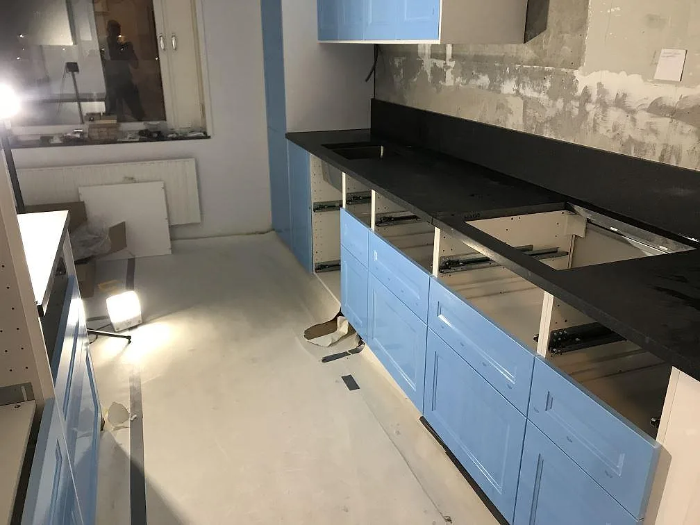 Köksbänkskiva i matt Nero Assoluto granit längs ett kök med ljusblå luckor i Malmö, fotograferad under montering.