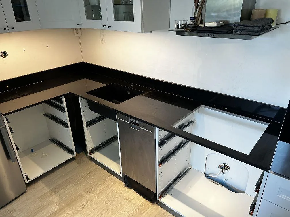 U-format kök i Malmö med polerad Nero Assoluto granit, låg svart stänkkant, rostfri diskhozon och urtag för häll.
