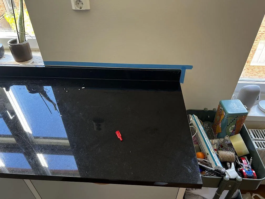 Närbild av polerad Nero Assoluto köksbänkskiva i Malmö med blank svart yta, stänkkant och fönsternisch.