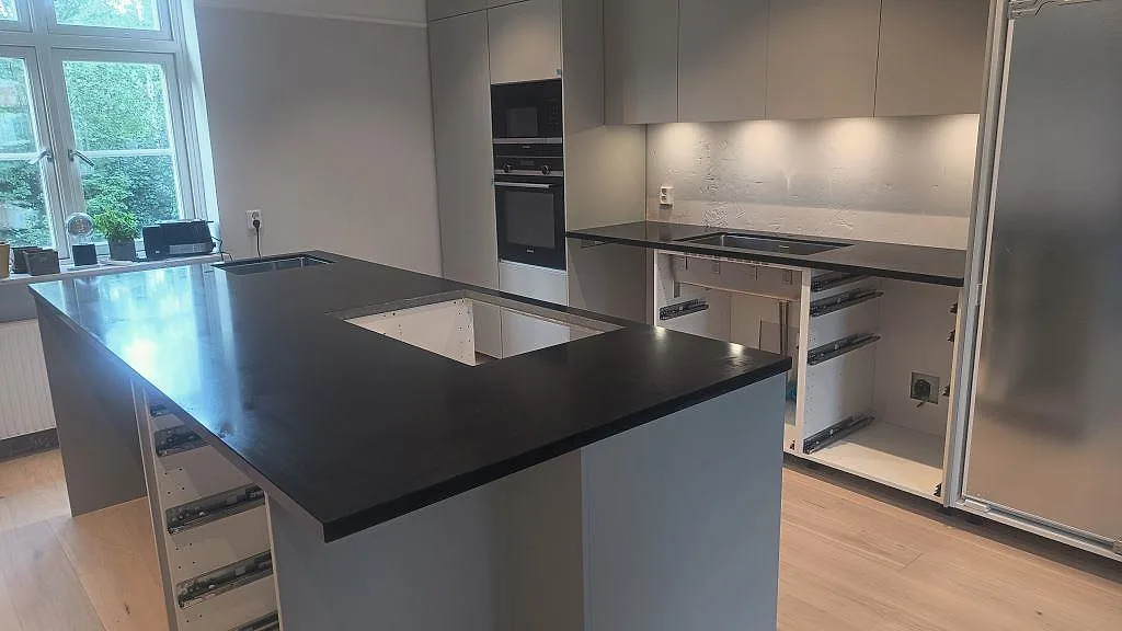 Köksbänkskiva i Nero Assoluto granit, matt 30 mm, med stor köksö, rostfri underlimmad diskho och ljusa golv i Malmö.