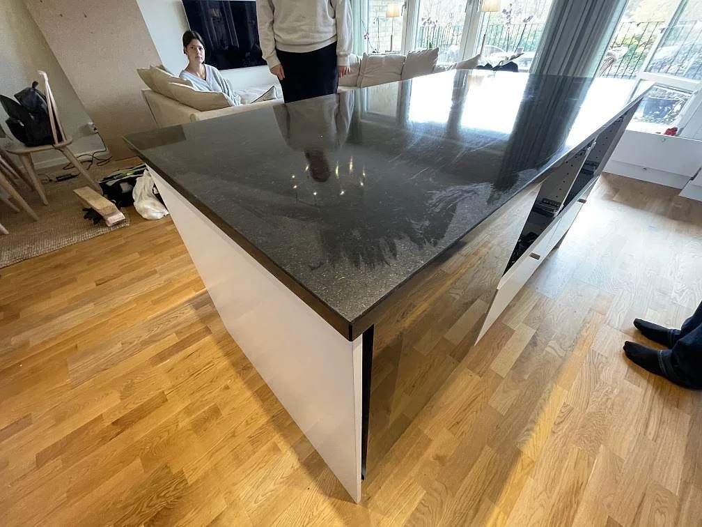 Blank Nero Assoluto granit som stor köksö i ett öppet kök och vardagsrum under montering i Malmö.
