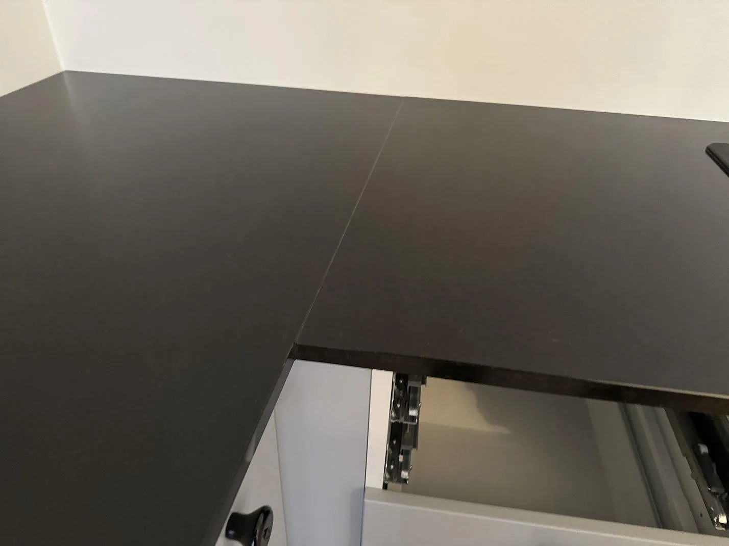 Skarv och framkant på matt Nero Assoluto granitbänkskiva över vita köksluckor i Malmö.