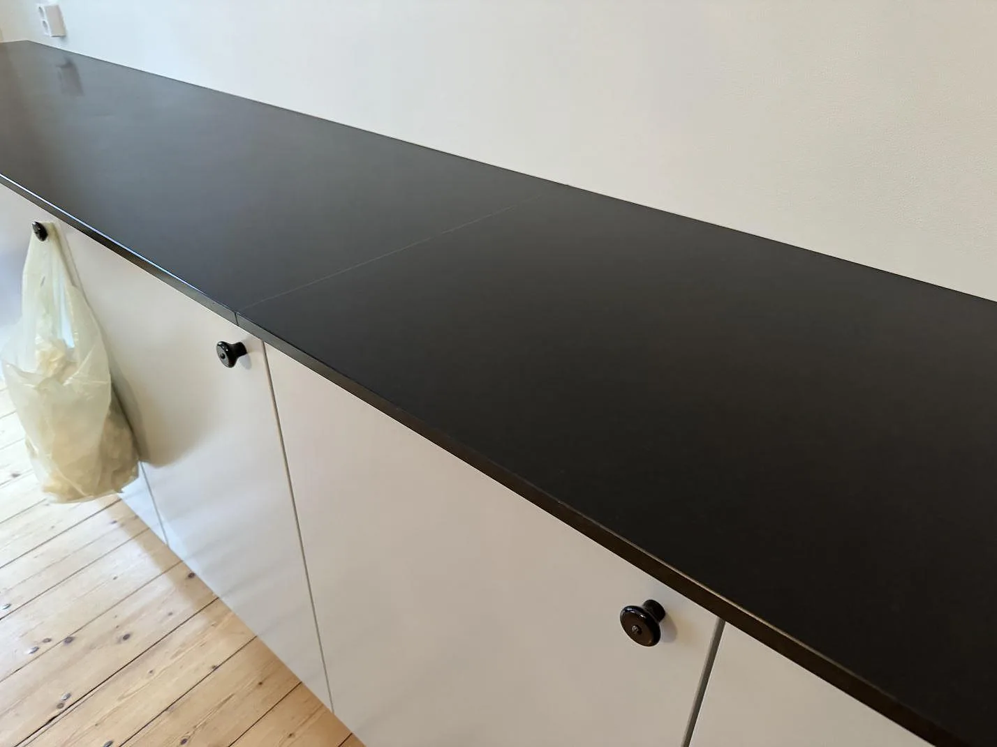 Lång rak del av köksbänkskiva i matt Nero Assoluto granit under montering i Malmö.