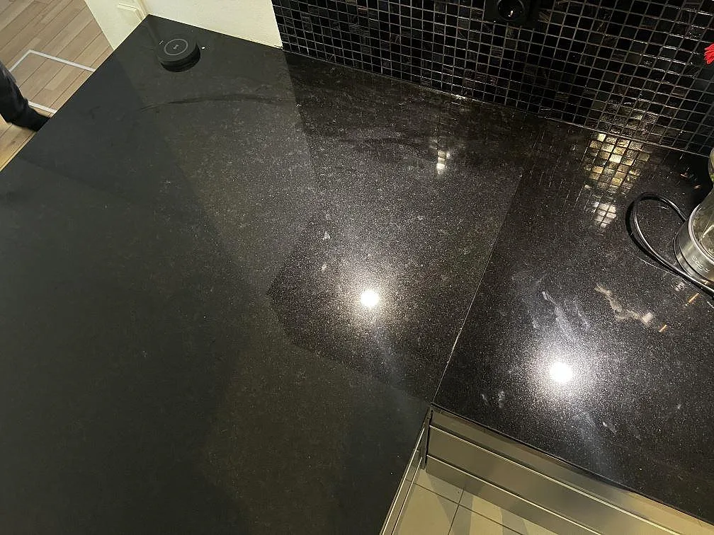 Polerad Nero Assoluto granit som köksbänkskiva intill mörk mosaik och vägguttag i Malmö.