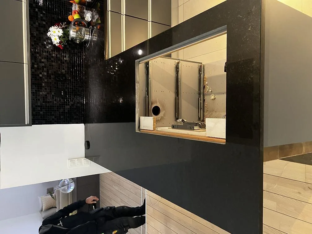 Polerad köksbänkskiva i svart Nero Assoluto granit med stor rektangulär öppning och mörk mosaik i ett kök i Malmö.