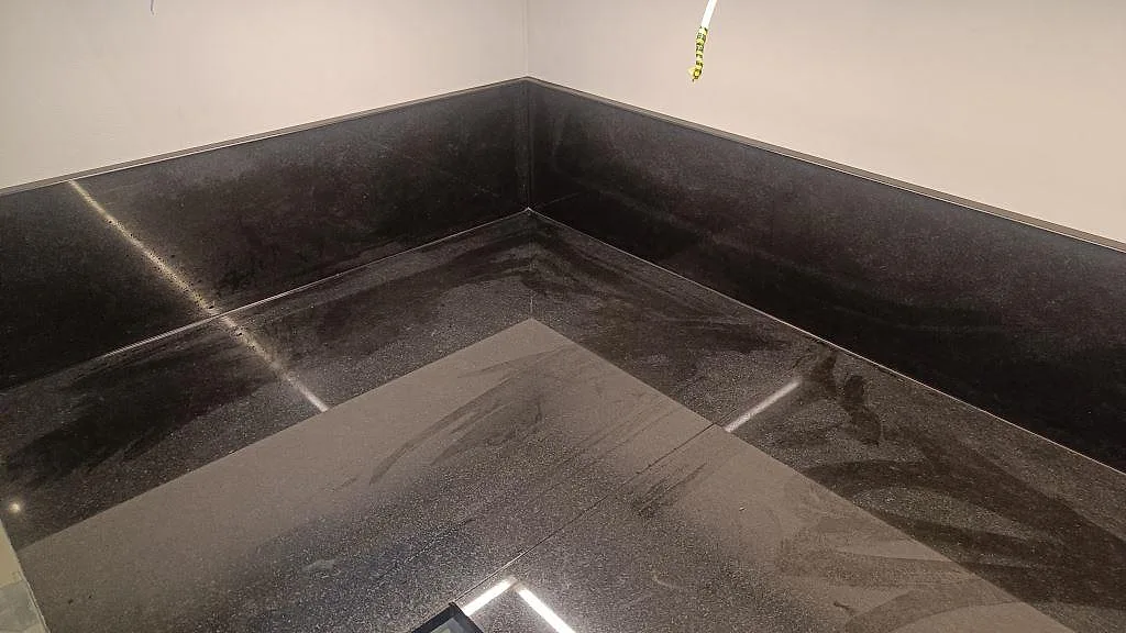 Hörnparti med blank Nero Assoluto köksbänkskiva och matchande stänkskydd under montering i Malmö.