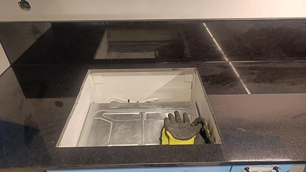 Hällurtag i polerad Nero Assoluto-granit med svart stänkskydd och blå köksinredning i Malmö.