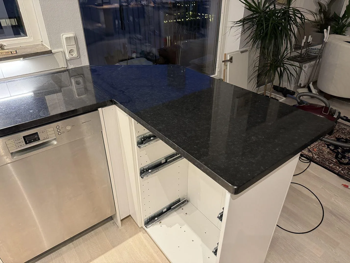 Polerad Nero Assoluto granit som köksbänkskiva vid fönster och diskmaskin i ett kök under montering i Malmö.