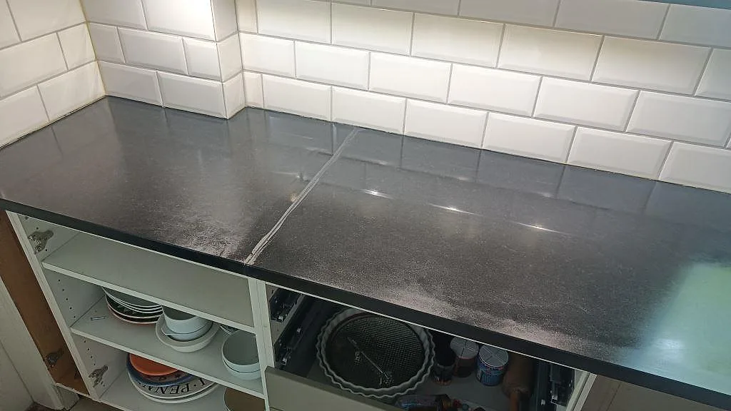 Hörnparti med skarv i matt Nero Assoluto granit och vit subway-kakelvägg i ett Malmö-kök.