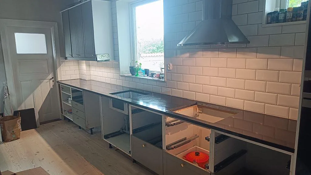 Köksbänkskiva i matt Nero Assoluto granit med diskho- och hällurtag i ett kök med vitt kakel i Malmö.