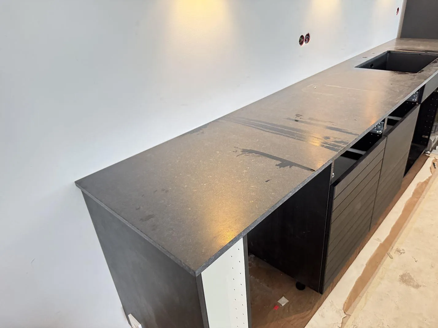 Köksbänkskiva i matt Nero Assoluto granit, 20 mm, på lång väggbänk med synlig öppning i Malmö.
