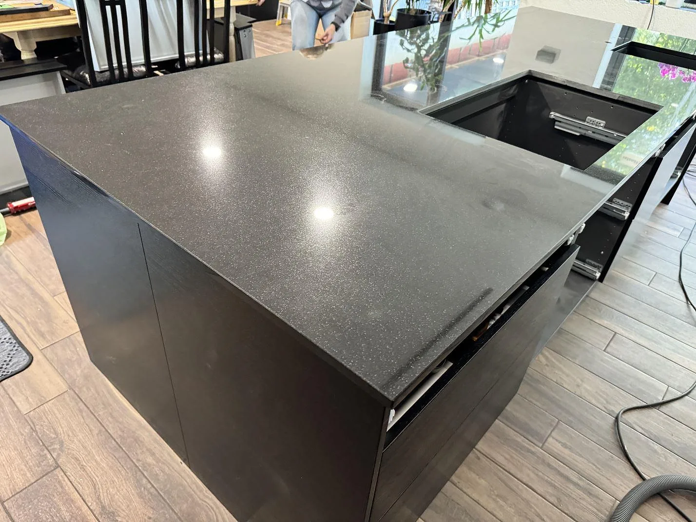 Närbild av finprickig polerad Nero Assoluto granit på köksö med blank yta och öppet urtag i Oxie.