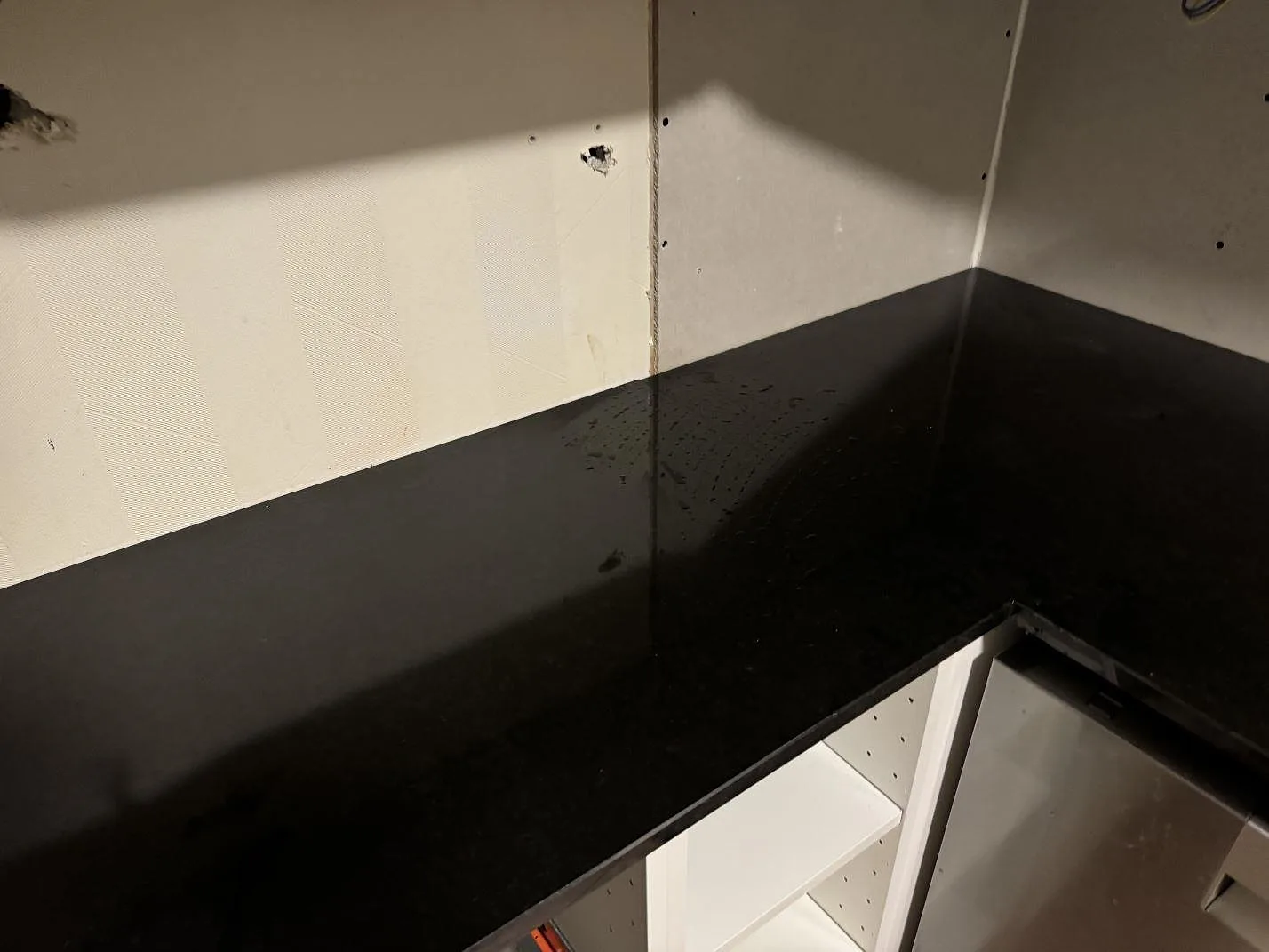 L-format hörn i polerad Nero Assoluto granit som köksbänkskiva mot vägg i Oxie.