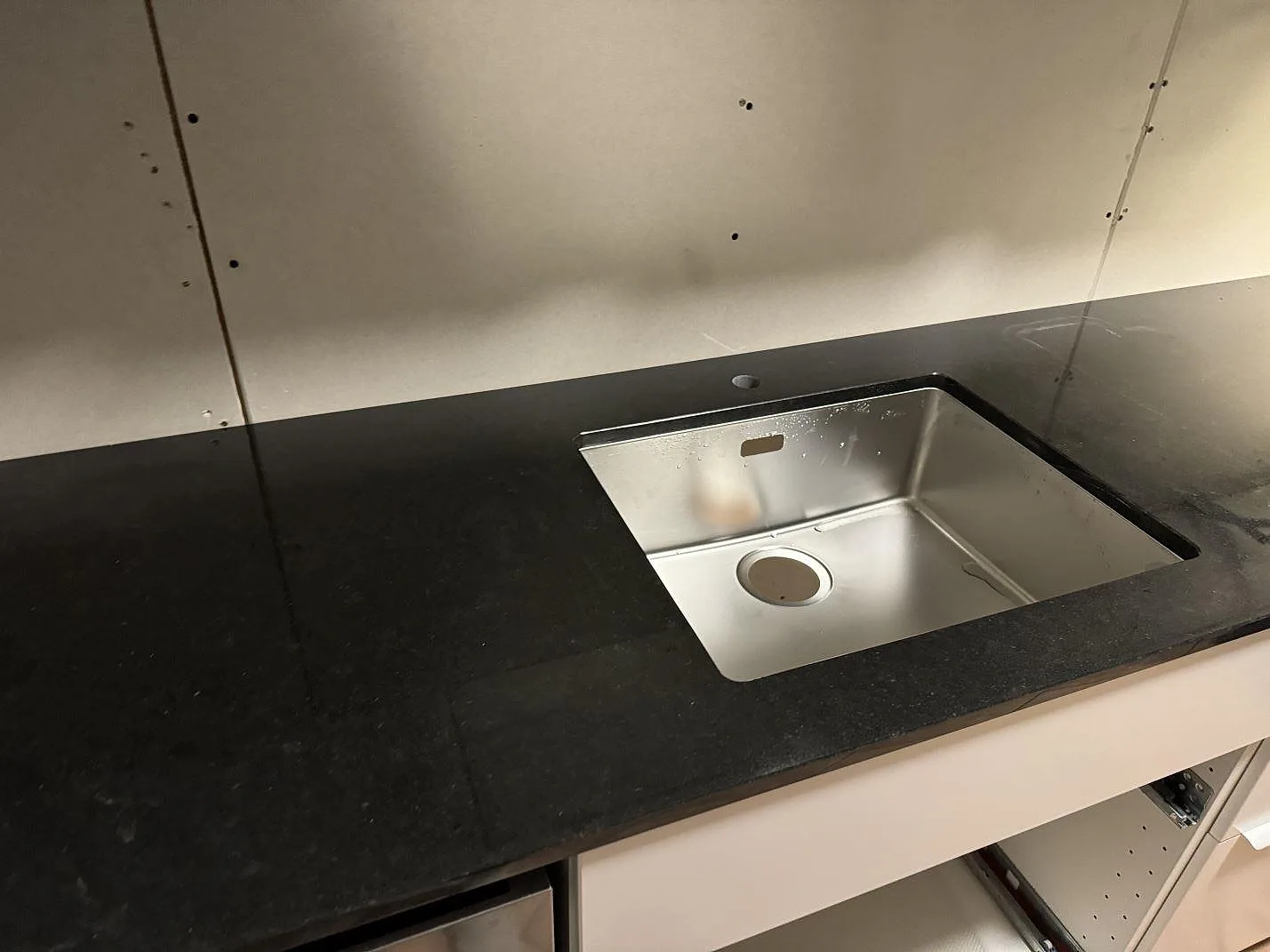 Köksbänkskiva i polerad Nero Assoluto granit med rostfri diskho monterad i den mörka stenen i Oxie.