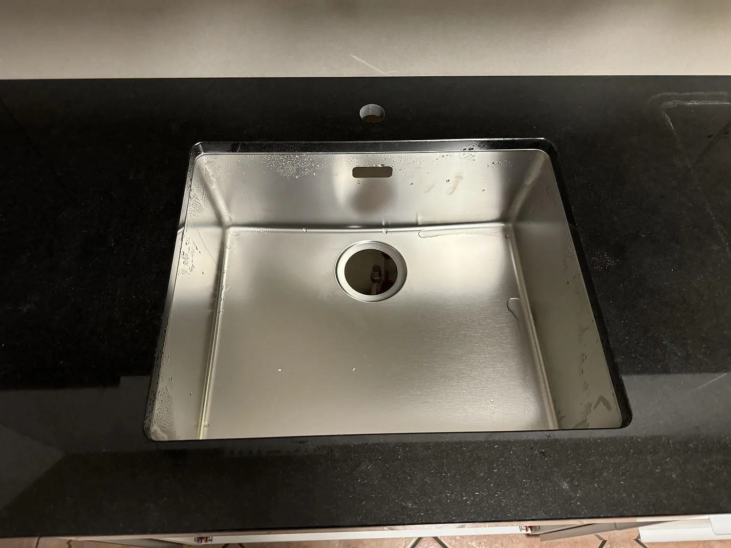 Närbild på rostfri diskho i polerad Nero Assoluto granit för köksbänkskiva i Oxie.