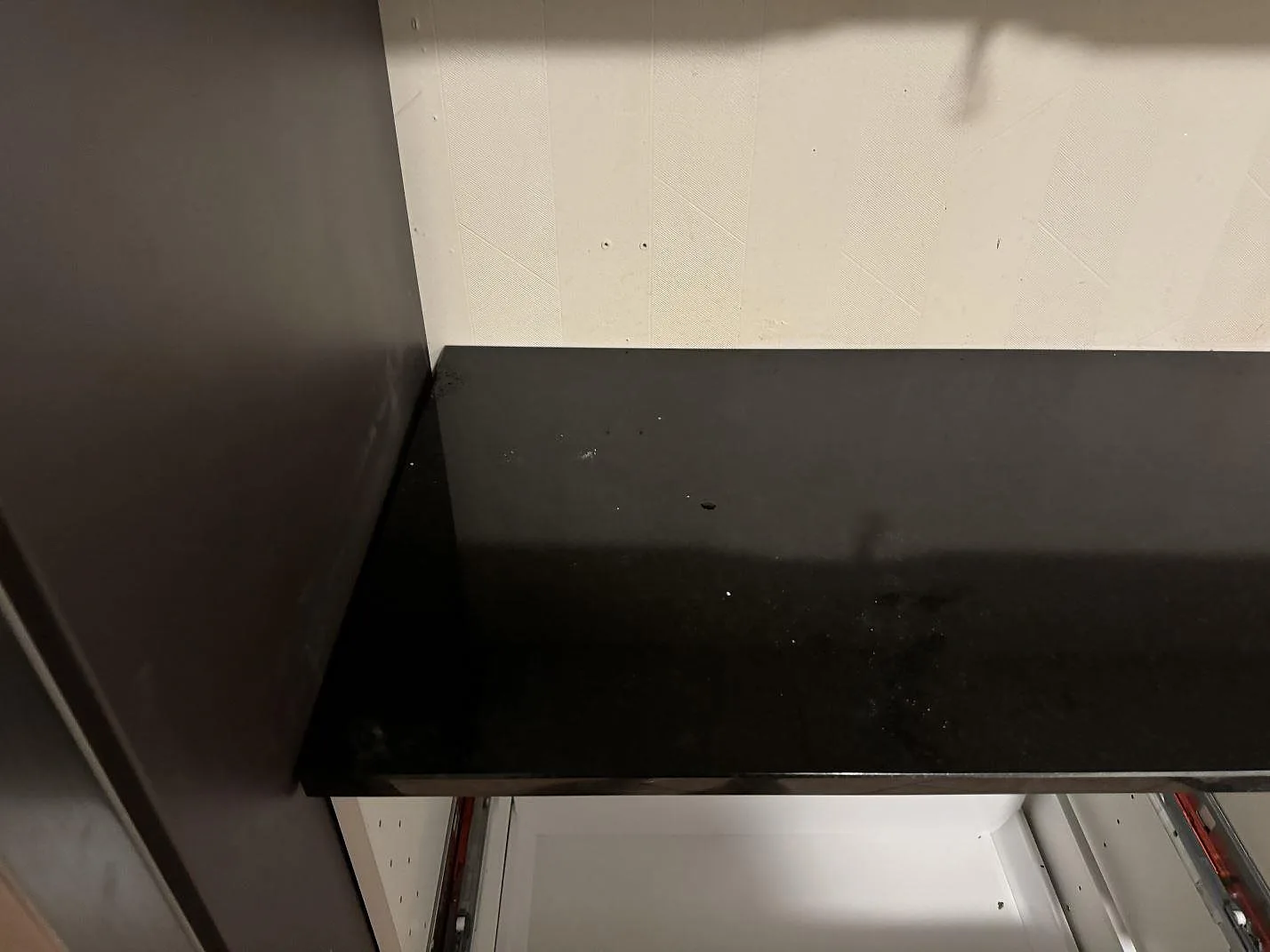 Rak bänkyta i polerad Nero Assoluto granit på vita köksstommar i Oxie.