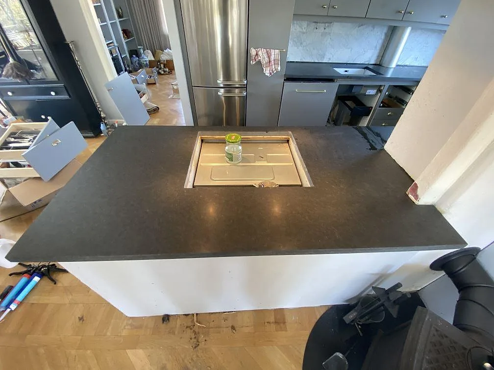 Stor köksö i matt Nero Assoluto, granit, med fräst hällurtag uppifrån under installation i ett kök i Sävedalen.