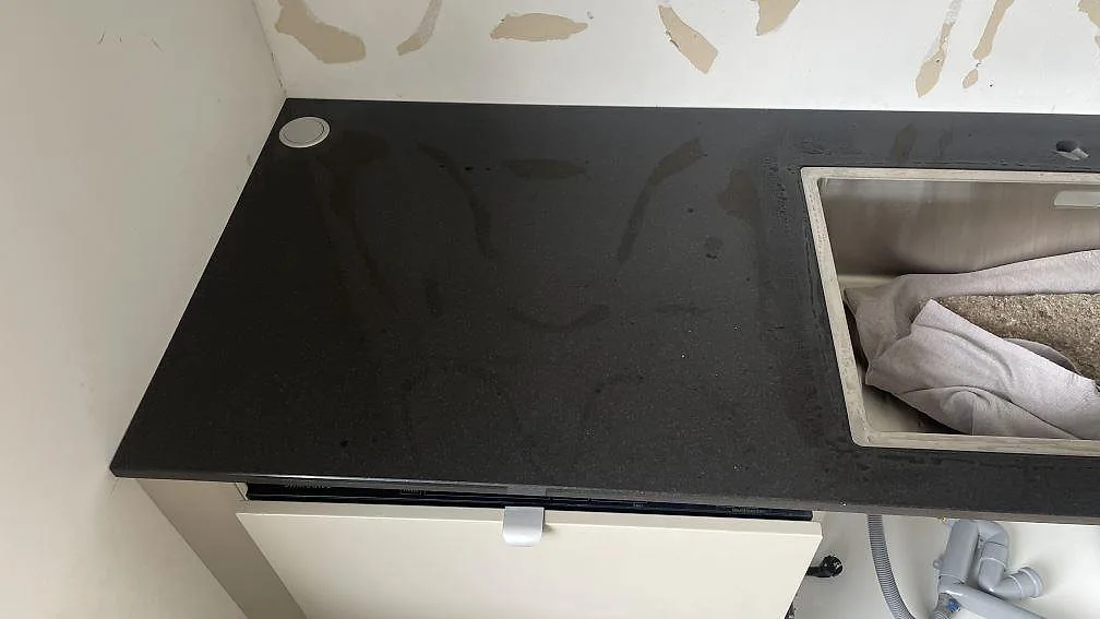 Polerad svart granit Nero Assoluto med rostfri diskho och blank arbetsyta längs väggen i Skurup.