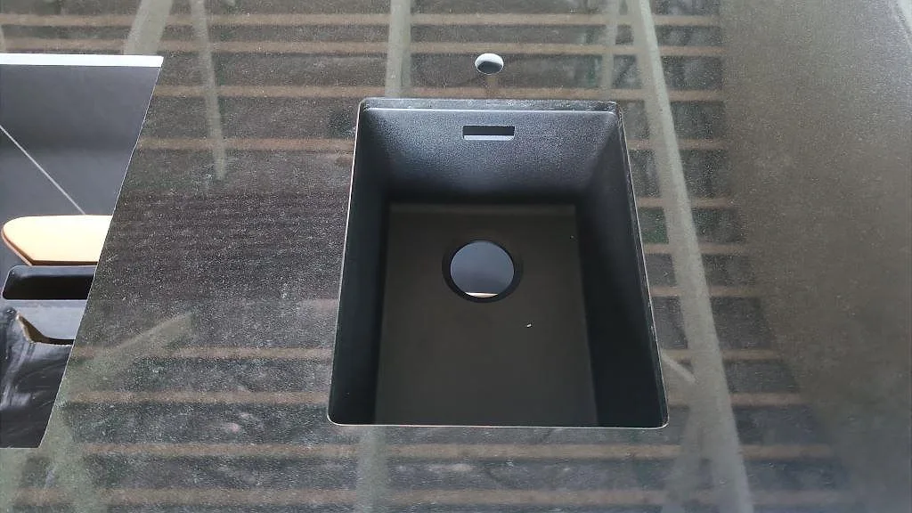 Närbild av svart diskho monterad i polerad Nero Assoluto granit på en köksö i Staffanstorp.